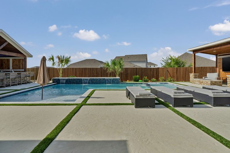 Pool with a tiled sheer descent wall and turf inlaid deck