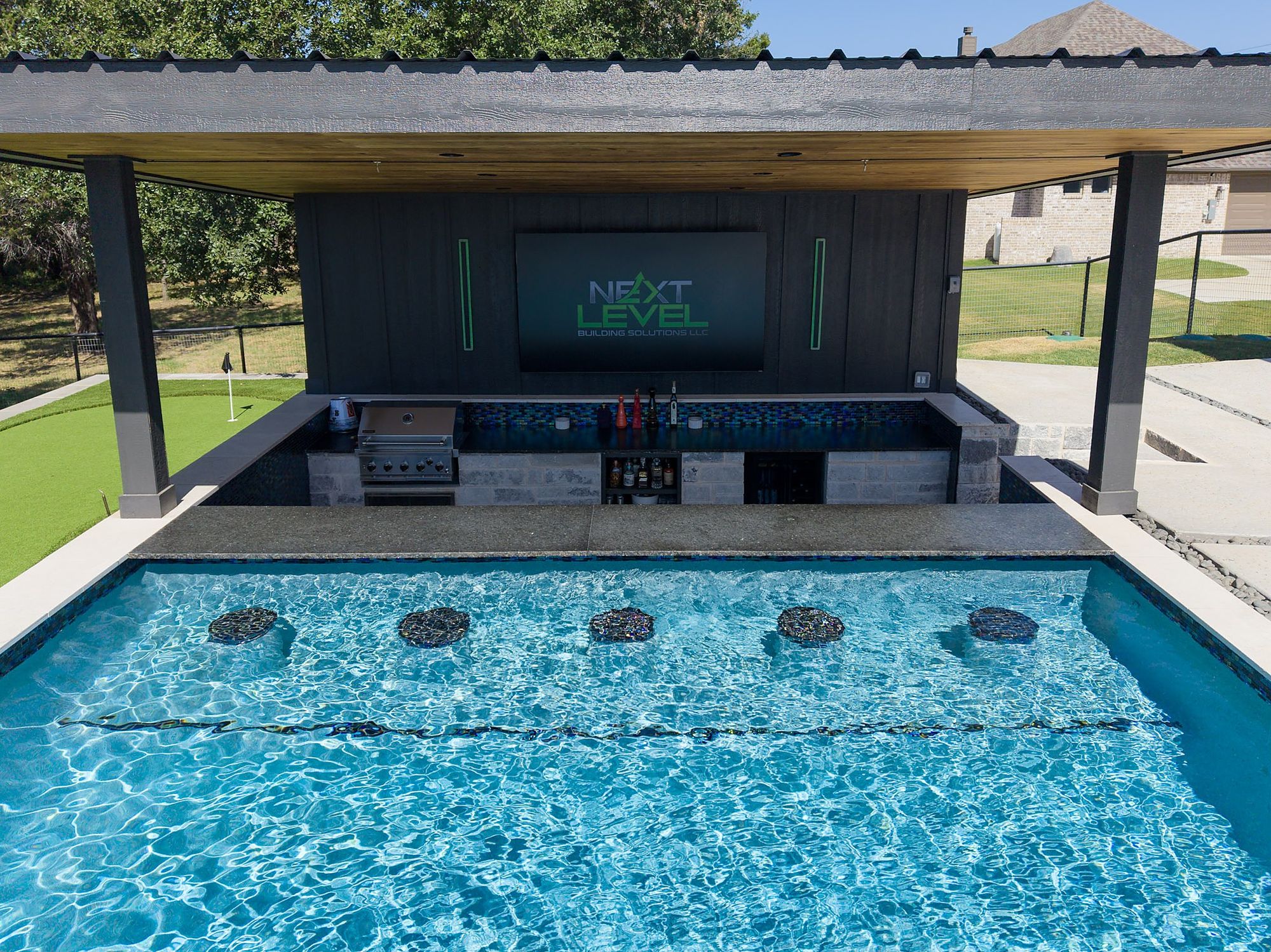 Swim up bar with submerged stools under a pavilion, built by Next Level